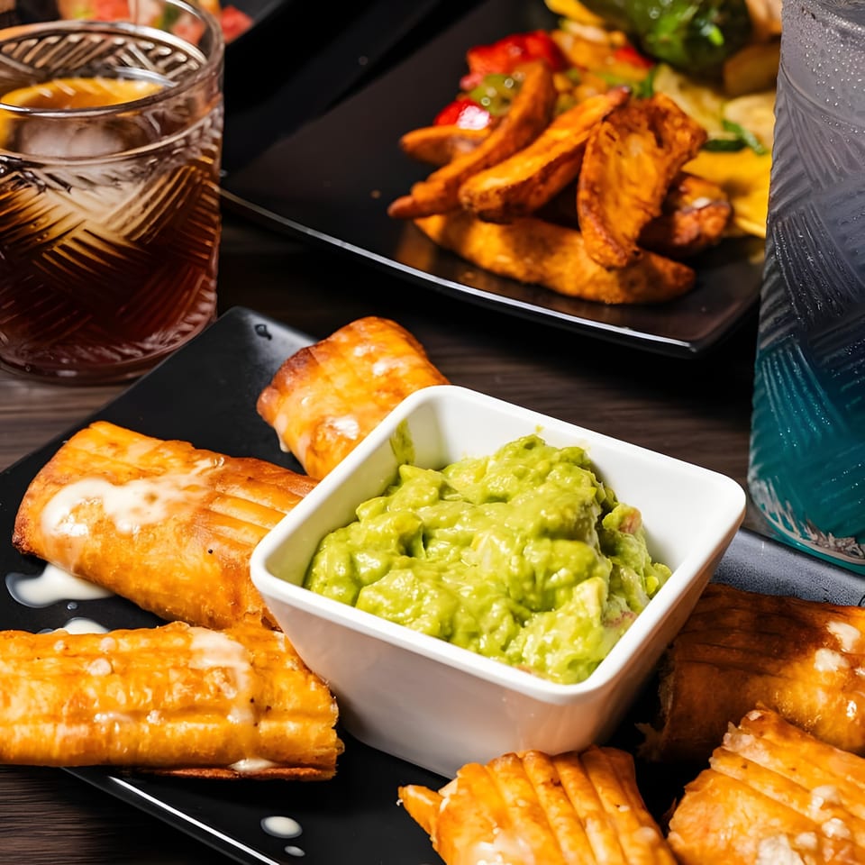 Crispy golden flautas with a side of guacamole, alongside sweet potato fries and drinks.